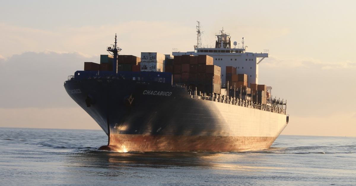 Cargo ship sailing across open ocean waters under clear skies, representing maritime decarbonization regulations and the global push for lower emissions in ocean freight.